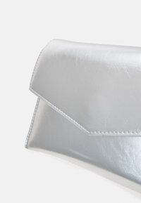 Stříbrná kabelka na ruku vyrobená z hladkého syntetického materiálu; má obálkovou klopu a jemné švy podél okrajů.