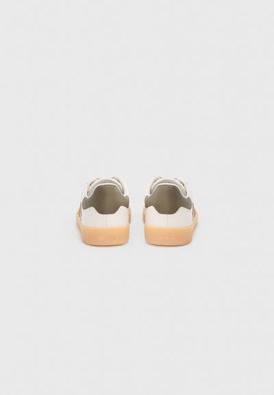 Λευκά και ελαιόχρωμα αθλητικά παπούτσια με διάτρητο σχέδιο, λαστιχένια σόλα και στρογγυλεμένη φτέρνα, με αντιθετικές υφές και ελάχιστη σήμανση.