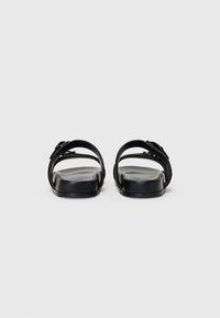 Sorte sandaler med to brede stropper, flat såle og glatt overflate. Minimalistisk design med et strømlinjeformet utseende og ingen synlige dekorasjoner.