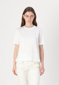 Hvid bomulds t-shirt med rund hals og korte ærmer. Har et lille logo på brystet og en afslappet pasform. Sammen med lyse bukser.