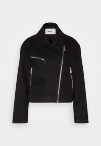 Veste noire courte en mélange de laine, dotée d'un col pointu, de plusieurs poches zippées et d'une texture lisse avec des accents en matériel argenté.