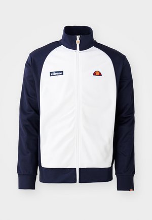 Weiße und marineblaue Zip-Jacke aus glattem Stoff. Sie verfügt über einen hohen Kragen, ein sportliches Design und ein Logo auf der Brust mit farblich abgesetzten Ärmeln.
