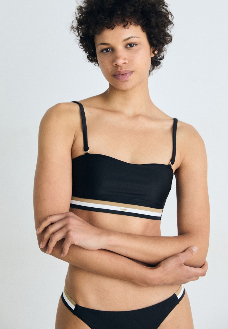 Bikini nero a due pezzi con top corto caratterizzato da spalline regolabili e una fascia decorativa bianca e dorata. Texture liscia, design minimalista.