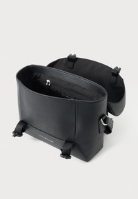 Sort skuldertaske med åben flap, frontspænder, lynlåslomme indeni og "Tommy Hilfiger" logo på frontpanelet.