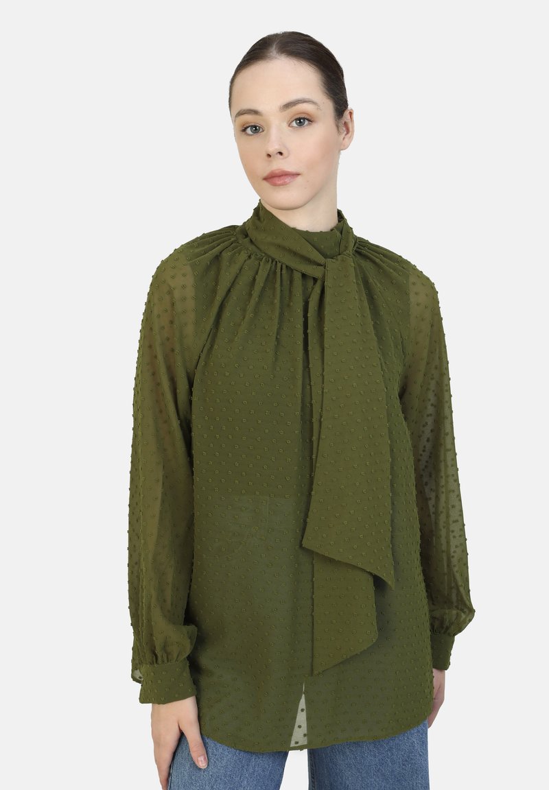 Olive green blouse made of lightweight, textured fabric with a tied neck and puffed sleeves, featuring small raised dots and a relaxed fit.
