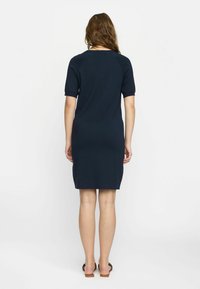 Robe bleu marine à manches courtes avec une coupe ajustée et longueur genou. Texture tricotée, design minimal et encolure ronde.