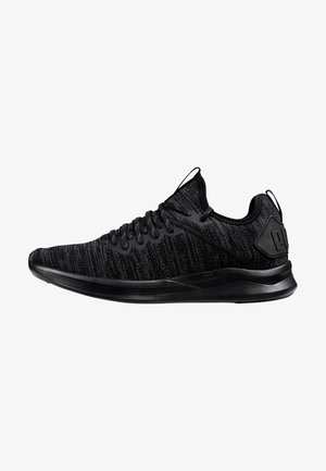 Baskets de sport basses noires avec tige en maille, fermeture à lacets, semelle coussinée et languettes de tirage sur la languette et le talon.