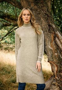 Abito maglione in beige chiaro con collo alto e strisce bianche a contrasto. Maniche e orlo a costine, che conferiscono un aspetto texturizzato e accogliente.