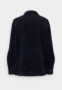Camicia in corduroy blu navy con maniche lunghe, dotata di colletto e dettagli con bottoni sui polsini, che presenta una texture a coste verticali.
