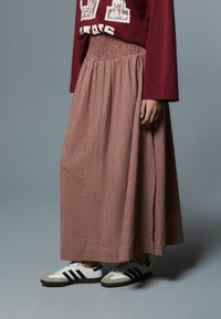 Pikk punase-valge ruuduline seelik, millel on kortsukujuline vöökoht, kombineeritud valgete ja mustade tossudega. Sile kangas ja pikkus kuni pahkluudeni.