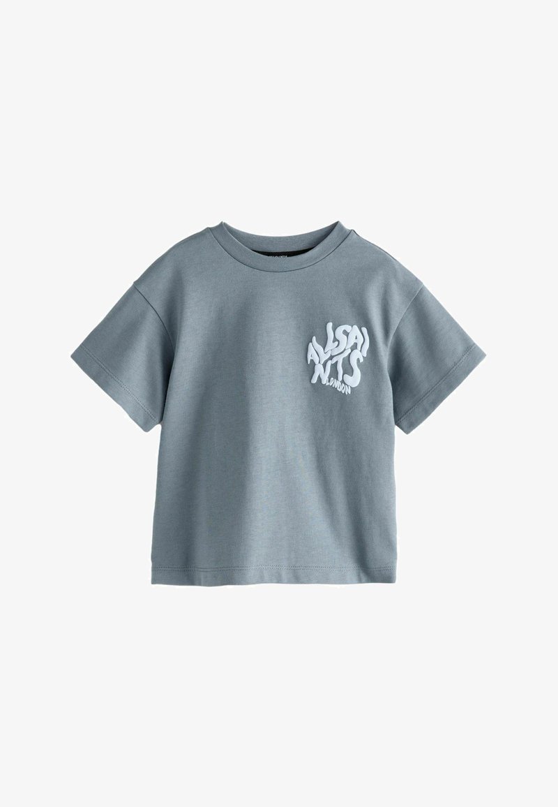 Svetle šedé trikoty s krátkým rukávem vyrobené z bavlny s kulatým výstřihem. Na přední levé straně má bílé grafické texty.