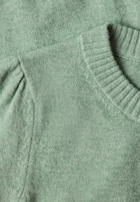 Gros plan d'un pull vert doux en tricot montrant un col rond côtelé et un détail froncé sur les manches.