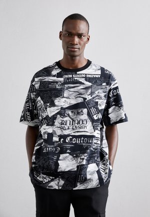 T-shirt graphique noir et blanc présentant un collage de texte et d'images, à manches courtes, col rond et coupe décontractée.