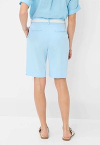 Pantaloni corti azzurri con una consistenza liscia, dotati di due tasche posteriori e una vita con una cintura bianca a contrasto.