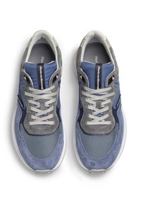 Siniset ja harmaat tennarit, joissa yhdistyvät samettiset ja verkkomateriaalit, litteillä nauhoilla ja pehmeällä vuorauksella. Paksu valkoinen pohja.