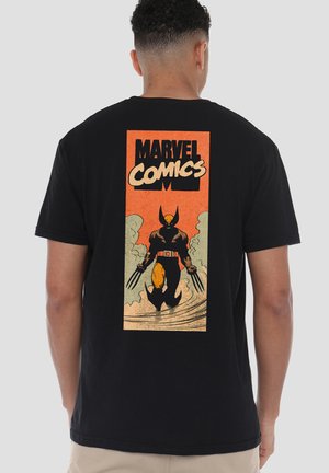 Person trägt ein schwarzes T-Shirt mit Vintage-Stil Marvel Comics Grafik, die Wolverine mit ausgestreckten Krallen auf dem Rücken zeigt.