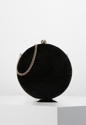 Ronde clutch van zwart fluweel met een gouden kettingriem en een metalen sluiting, met een gladde textuur en een minimalistisch ontwerp.