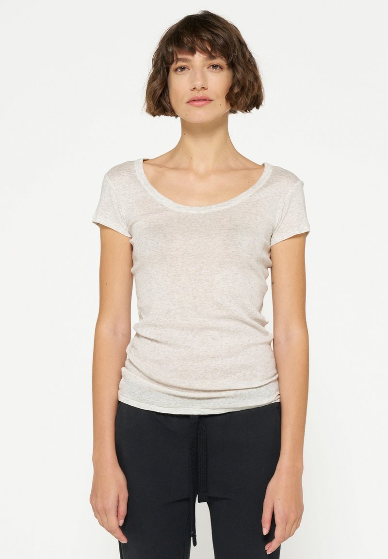 T-shirt a maniche corte, con scollo a barca, di colore beige chiaro, realizzato in un tessuto morbido e texture, con una silhouette aderente e un lieve drappeggio rilassato.