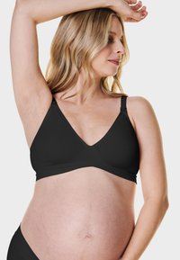Czarny stanik ciążowy z dekoltem w kształcie V, regulowanymi ramiączkami, miękkim materiałem i bezszwową konstrukcją, dostosowujący się do rosnącego brzucha.