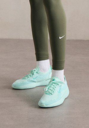 Sneakers Nike verde menta chiaro con tomaia in rete e suola testurizzata, abbinati a leggings verde oliva e calze bianche.