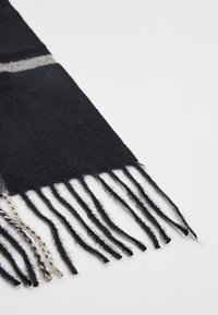 Czarny wełniany szal o miękkiej fakturze, z szarą paskiem i frędzlami na końcach. Wykończony prostym, schludnym wzorem.