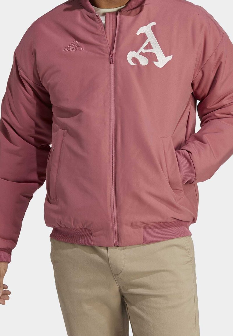 Rosa bomberjacka med dragkedja fram, ribbade ärm- och nederkanter, med en vit broderad bokstav 'A' och logotyp på vänster bröst.