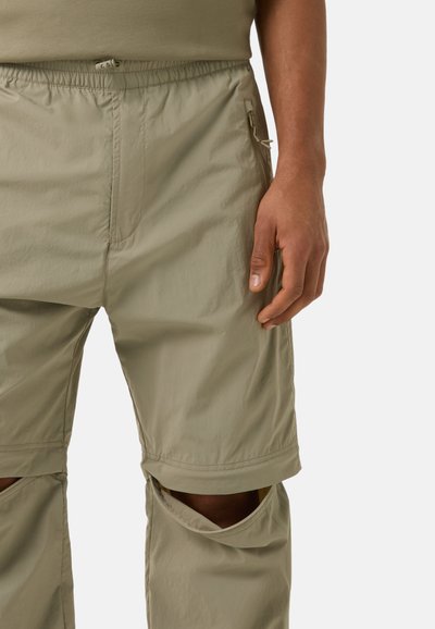 Helle grüne, cropped Hosen mit elastischem Bund, seitlichen Taschen und mit Reißverschlüssen an den Knien für eine verstellbare Länge. Glattes, leichtes Material.