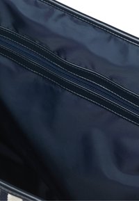 Navy Nylon Tasche im Inneren mit einem Reißverschlussfach, das eine glatte Textur und gestickte Akzente zeigt. Entwickelt für Organisation und einfachen Zugriff.