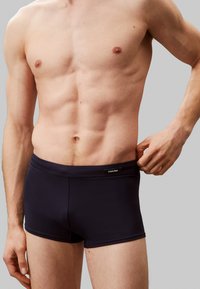 Granatowe bokserki z gładkiego materiału o dopasowanym kroju. Posiadają logo Calvin Klein na pasku. Brak widocznych wzorów lub akcentów.