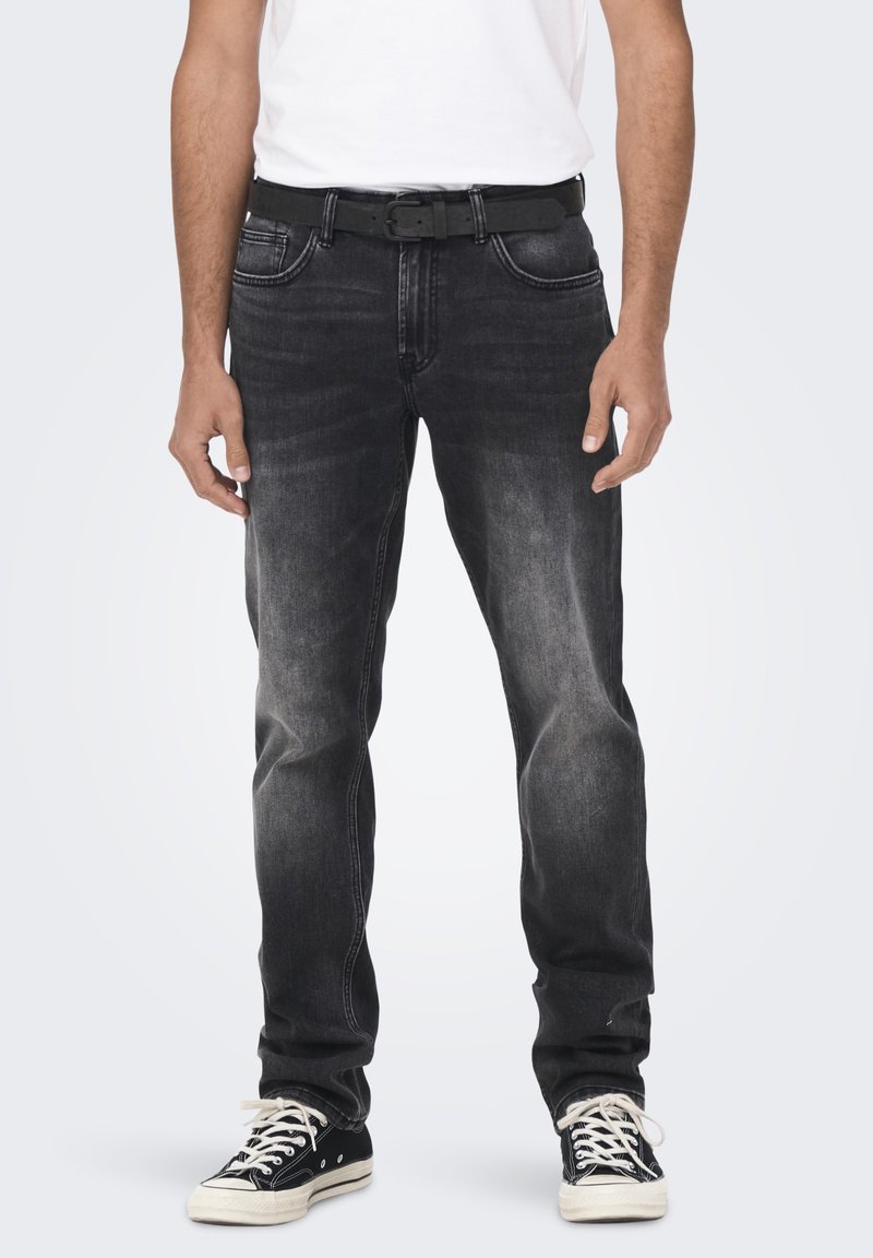 Zwarte spijkerbroeken van denim met een vervaagde afwerking, voorzien van vijf zakken, riemlussen en een rechte snit, gecombineerd met zwarte sneakers.