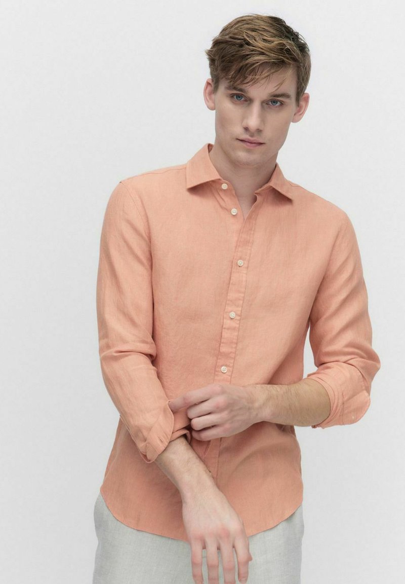 Licht koraalkleurig linnen shirt met een button-down kraag, lange mouwen opgerold bij de manchetten, slim fit en een iets afgeronde zoom.