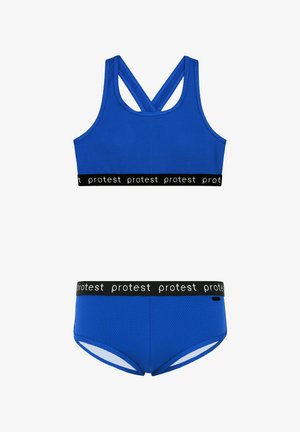 Sujetador deportivo azul con una tela texturizada, que cuenta con un diseño de espalda cruzada y una banda negra con "protesta" repetido. Parte inferior azul a juego.