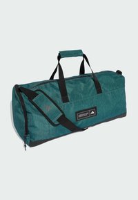 Groene sporttas van textured stof, met zwarte accenten, dubbele handvatten en een verstelbare schouderband; bevat een label met het merkembleem en tekst.