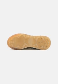 Suola di scarpa sportiva in gomma di colore marrone e beige con un motivo di grip testurizzato e forme geometriche in rilievo, progettata per aderenza e durata.