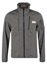 Szara lekka kurtka z wysokim kołnierzem, wieloma kieszeniami zapinanymi na zamek oraz gładką fakturą. Przód zapinany na zamek i naszywka z logo.