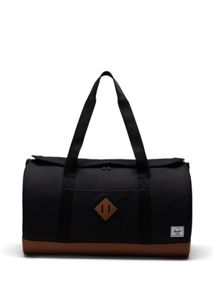 Sort duffel taske med brune læderdetaljer, der har to skulderremme, et diamant-logo patch og en lynlåsåbning. Tekstureret stof.