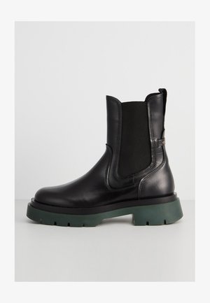 Black leather Chelsea boot with elastic side panels and thick dark green rubber sole shown from the side on a white background.
