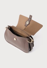 Sac à main en cuir marron avec fermeture à rabat, quincaillerie dorée et texture lisse. L'intérieur comprend une doublure beige et plusieurs poches.