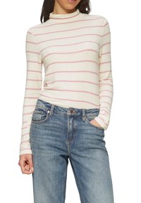 Langärmliges cremefarbenes Oberteil mit pinken horizontalen Streifen, rundem Ausschnitt, kombiniert mit blauen Jeans. Glatter Stoff, taillierter Schnitt.