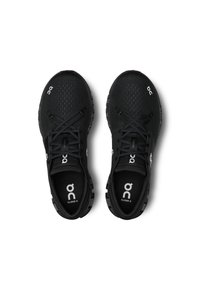 Baskets de sport noires avec une tige en mesh respirant, un design texture, des lacets et une semelle rembourrée. Présente un logo sur les côtés et la languette.