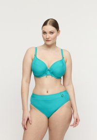 Set bikini a coste color verde acqua con reggiseno sagomato con spalline regolabili e dettaglio annodato, abbinato a slip a vita alta con dettagli circolari.