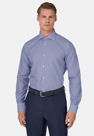 Blau-weiß gestreiftes Hemd mit langen Ärmeln, Knopfleiste und kontrastierenden Manschetten, kombiniert mit dunkelblauen Hosen und einem grünen Gürtel.