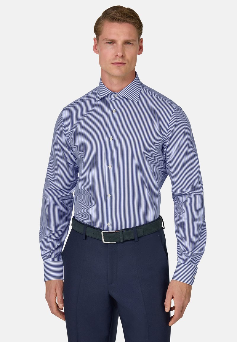 Camisa de vestir a rayas azules y blancas con mangas largas, tapeta de botones y puños en contraste, combinada con pantalones oscuros azules y un cinturón verde.