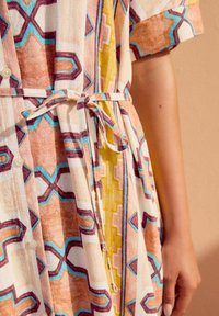 Vestito multicolore a motivi in tessuto leggero, con vita legata, maniche corte, bottoni e design geometrici in rosa, blu e giallo.