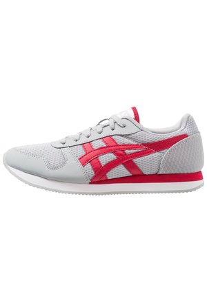 Witte en grijze sportieve schoen met rode strepen en accenten, vastgeknoopt, weergegeven vanaf de zijkant op een witte achtergrond.