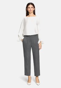 Witte satijnen blouse met pofmouwen, gecombineerd met lichtgrijze, op maat gemaakte broeken en crèmekleurige, puntige hakken, wat een moderne, professionele uitstraling creëert.