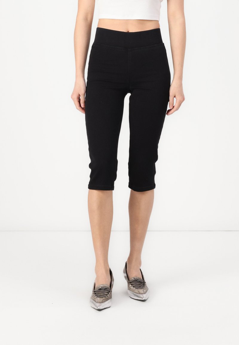 Svarte capri-bukser med høy midje, laget av stretchmateriale. Har en glatt tekstur og en tettsittende silhuett, som avsluttes rett under kneet.