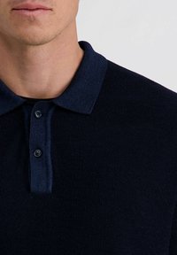 Marineblaues Strick-Poloshirt mit Kragen, zwei Knöpfen und strukturiertem Stoff. Verfügt über ein dezentes Muster und kurze Ärmel.