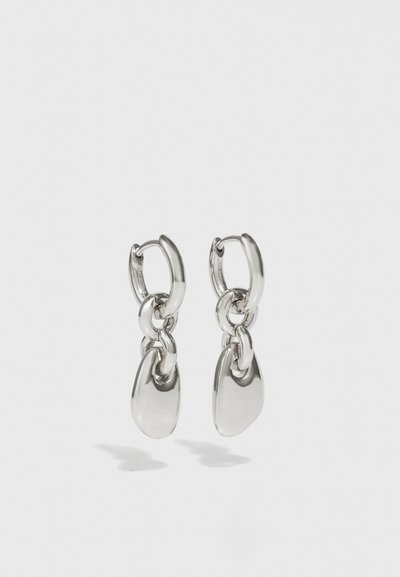 Boucles d'oreilles en argent avec des maillons ovales allongés, présentant une finition polie et un pendentif tombant texturé. Design simple avec des bords lisses.