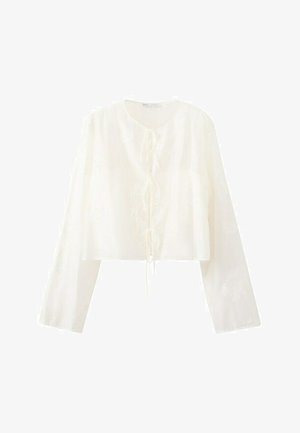 Bijela bluza dugih rukava s krojem do struka i tri kopče sprijeda, s diskretnim teksturiranim detaljima na tkanini.